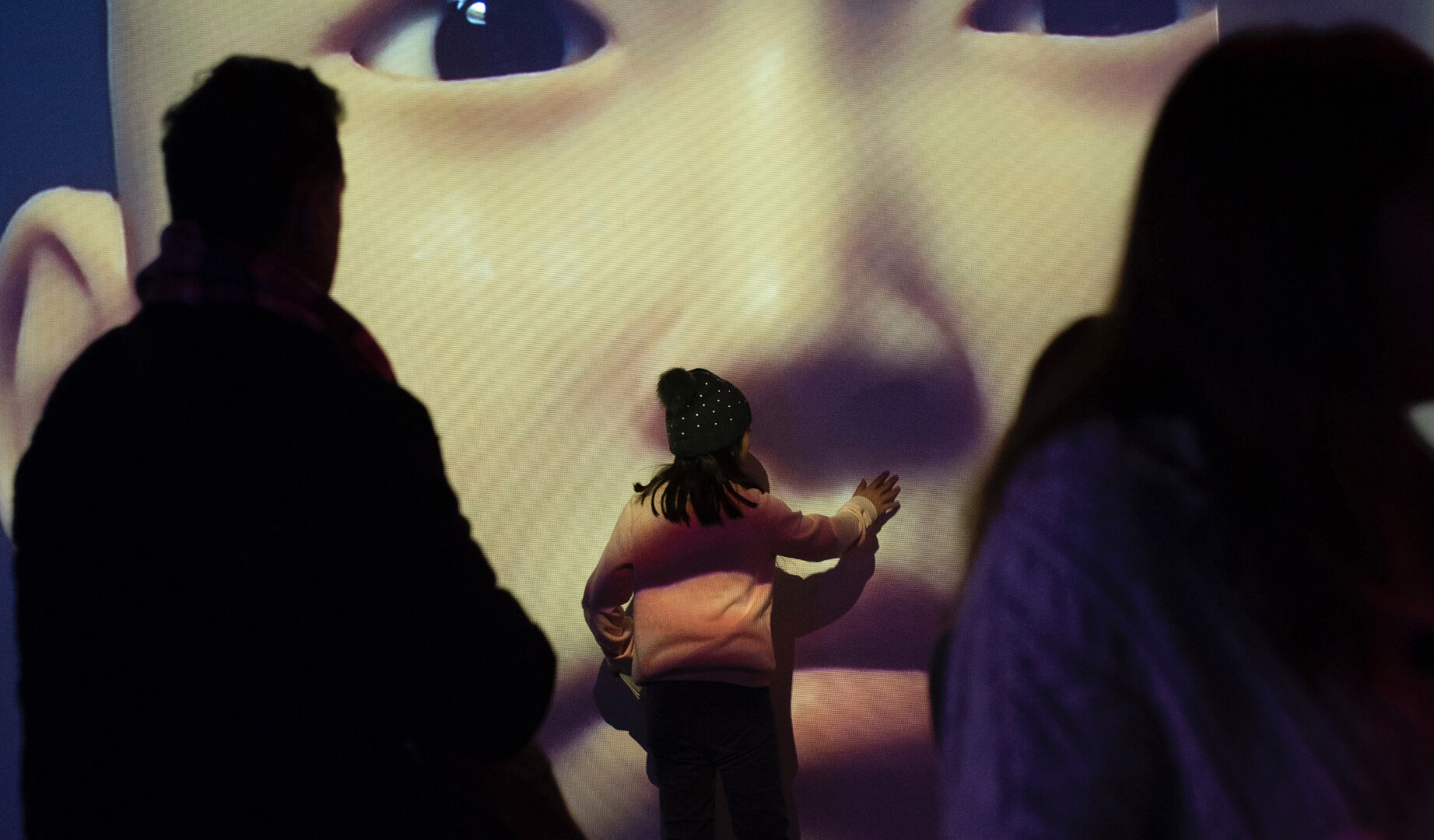 Niña pequeña enfrente de un mural gigante con la cara de una mujer asiática