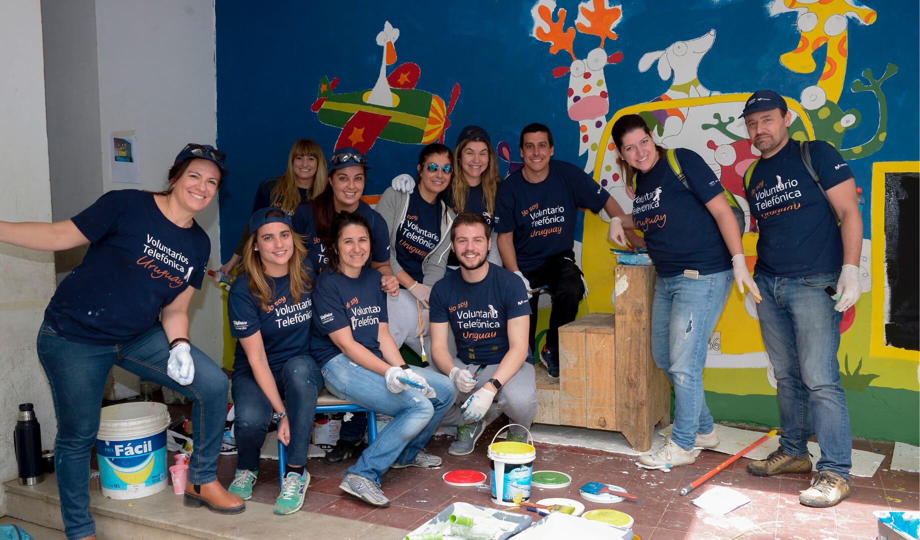 Voluntarios posando en una actividad de pintura de murales infantiles