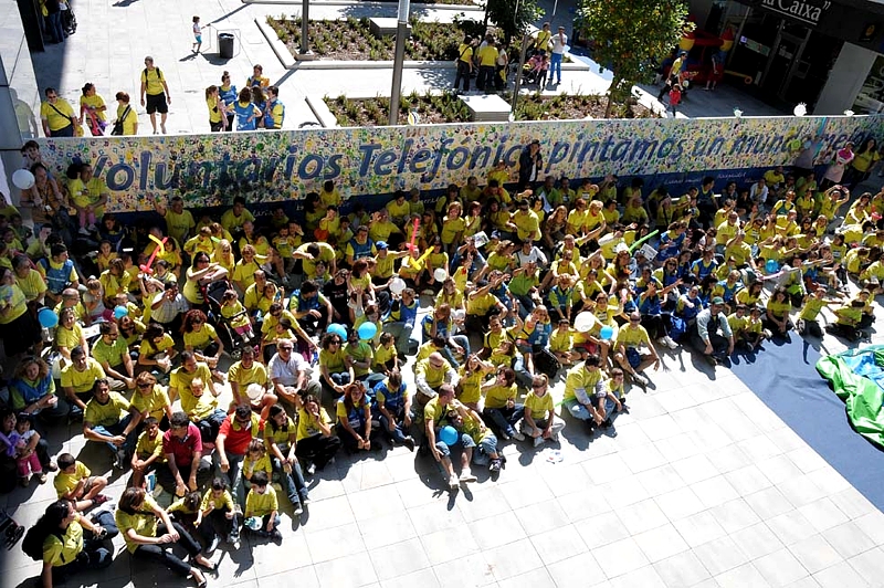 Un grupo de asistentes al evento, al pie del mural, símbolo de su compromiso con la solidaridad