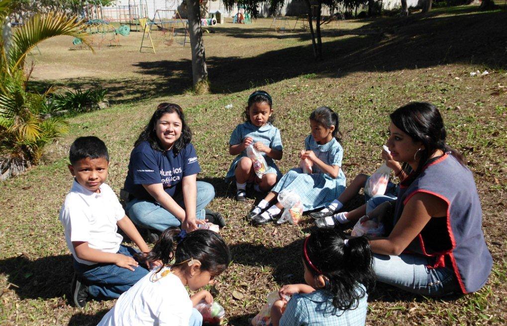 Los Voluntarios aprovechan el tiempo de recreo para compartir la refacción con los niños.