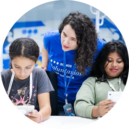 Voluntaria de Telefónica junto a dos niñas usando tabletas digitales