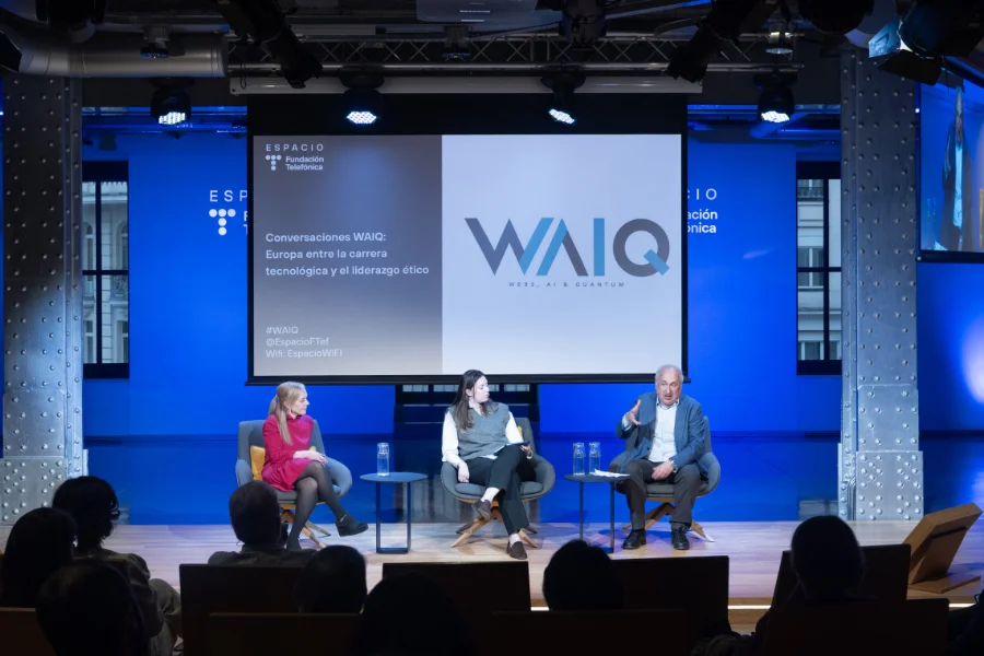 Escenario con tres personas en uno de los encuentros Conversaciones WAIQ